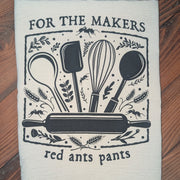Kitchen towel with cooking utensil design and text on a wooden surface