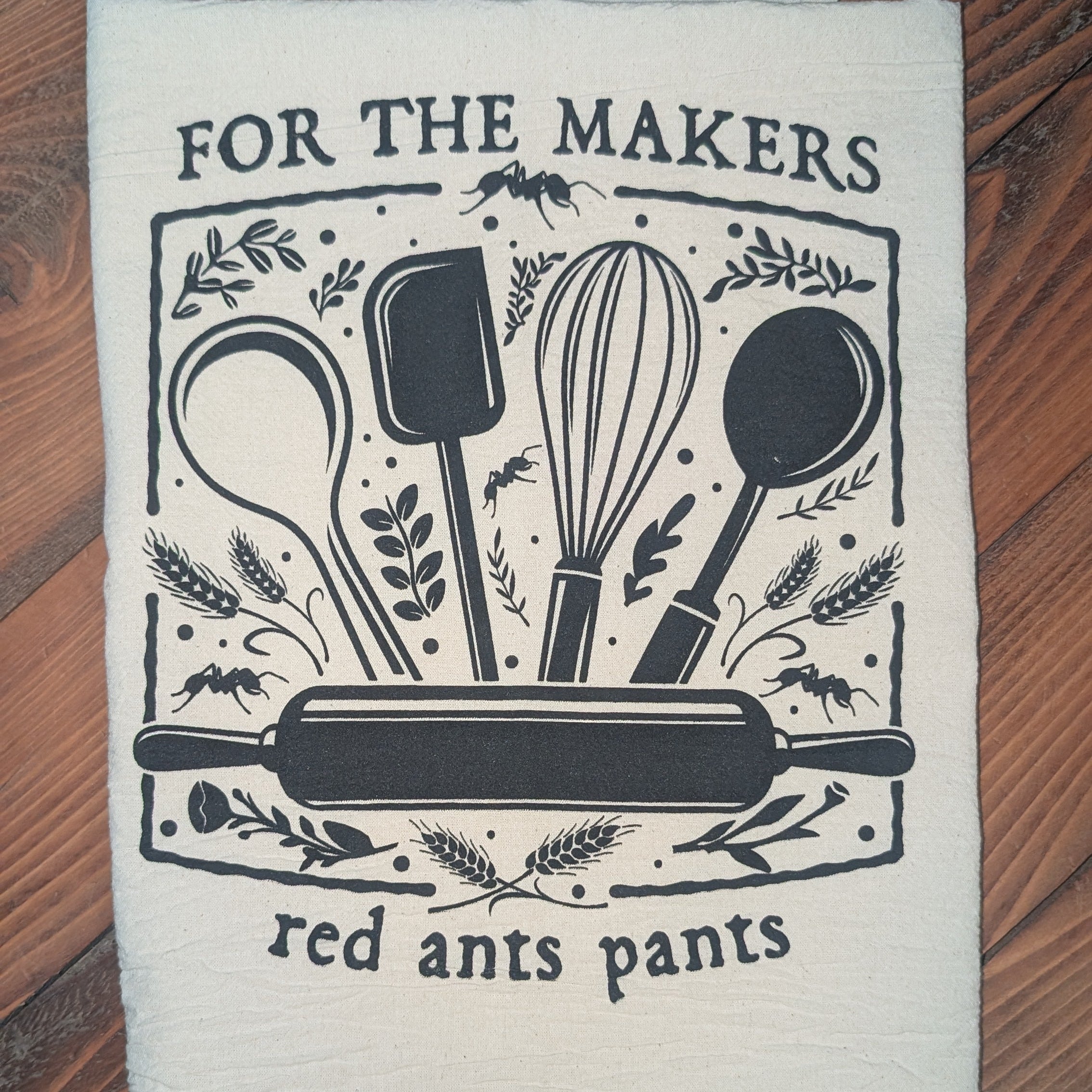 Kitchen towel with cooking utensil design and text on a wooden surface