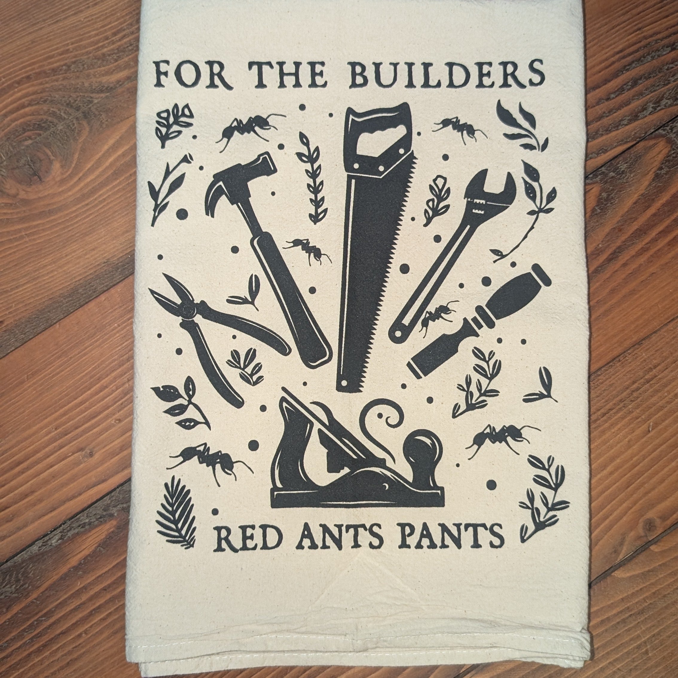 Fabric towel with construction-themed design and text on a wooden surface