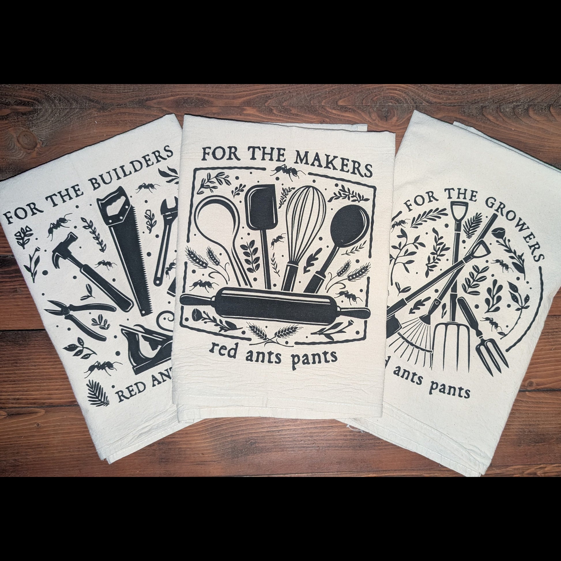 Set of three towels with black and white graphics on a wooden surface